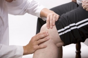 physical therapist examining a patient's knee